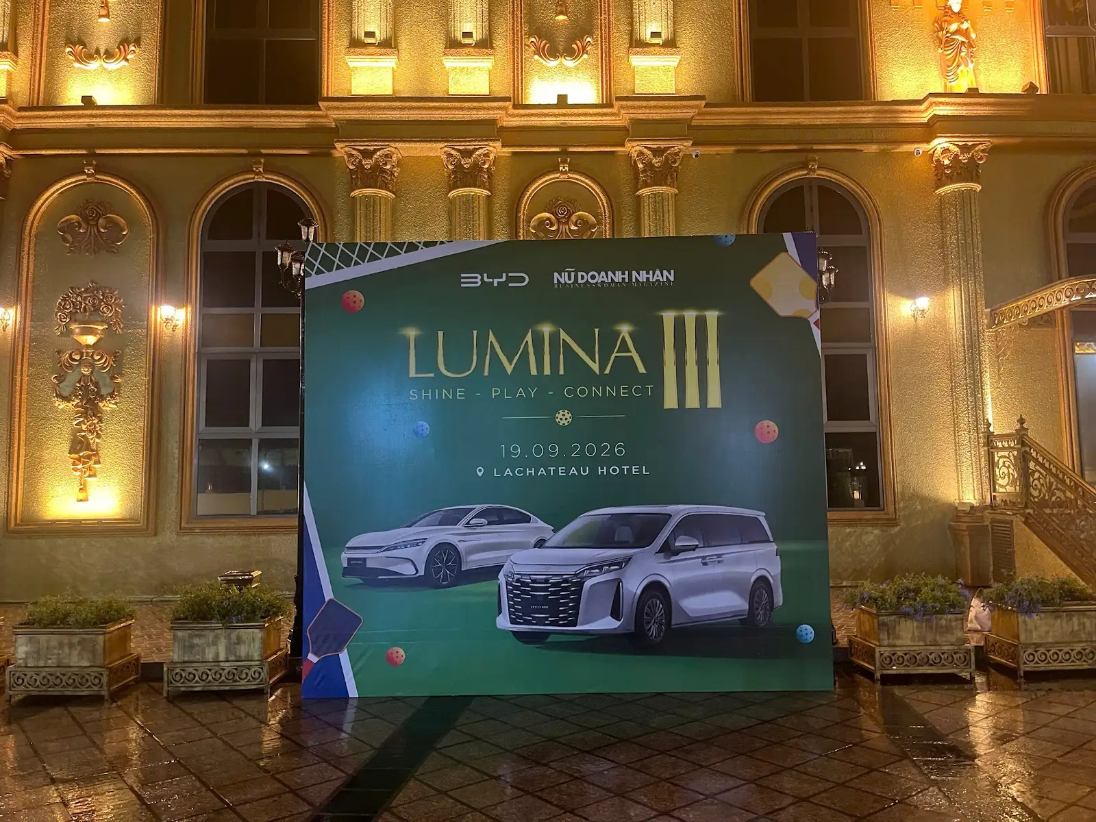 Backdrop Lumina III nền xanh với chữ vàng và hình hai ô tô trong kho tư liệu Trần Lê Show