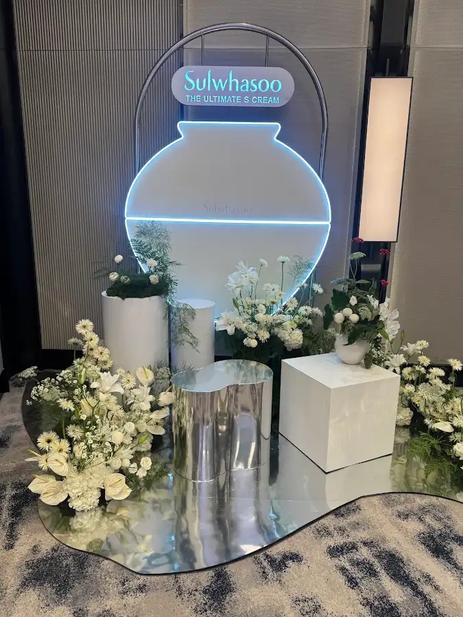 Booth Sulwhasoo với cụm trưng bày hình lọ mỹ phẩm và hoa trắng